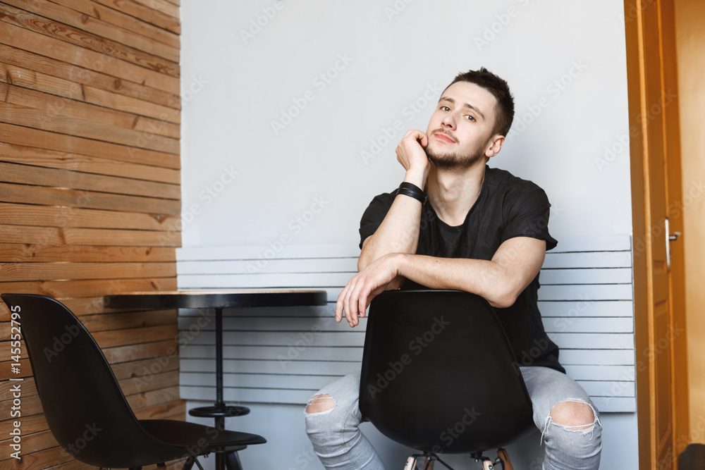 Guy with right hand on chairback, left and on chin. Guy with right hand on chairback, left and on chin.