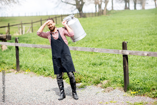 Bilde på lerret Full body portrait of a handsome milkman in apron with milk container outdoors o