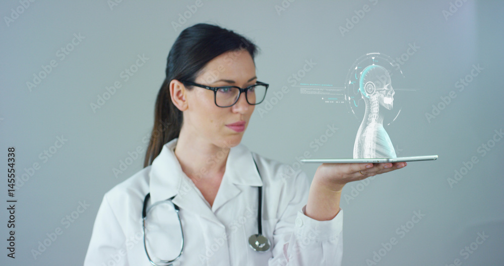Female doctor with white coat and stethoscope, with holographic tablet represented the patient's body, the heart lungs, muscles, bones. Concept: Futuristic medicine, world assistance, and the future.