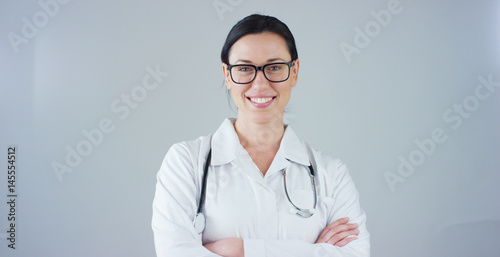 Slika na platnu Portrait of a female doctor with white coat and stethoscope smiling looking into camera on white background