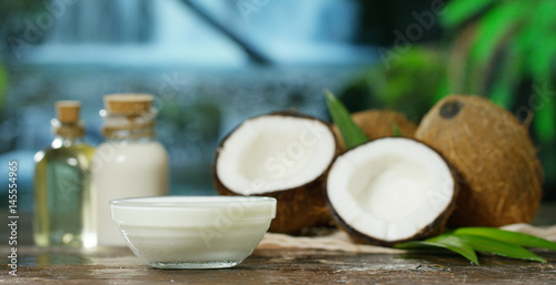 Fresh nourishing coconut milk moisturizing cream for hands, face and skin, on background of the waterfall, concept: spa, skincare, beauty, healthy lifestyle, bio products, ecologic products, massage.