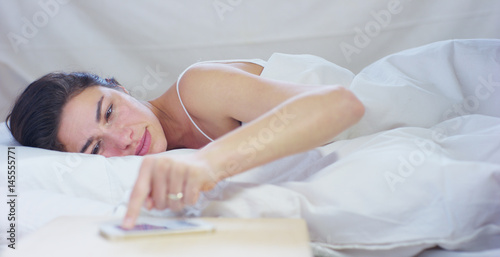 A simple working day for a beautiful young girl sleeping in a warm bed, covered with a soft warm white blanket, on a white background.