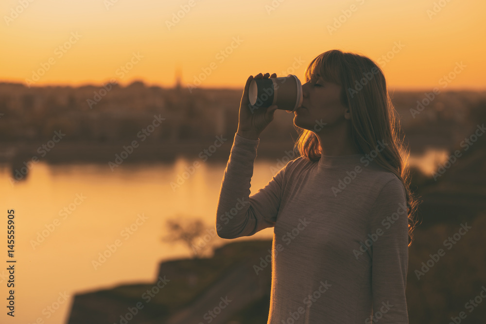 Silhouette of a woman drinking coffee at the sunset. Silhouette of a woman drinking coffee at the sunset.