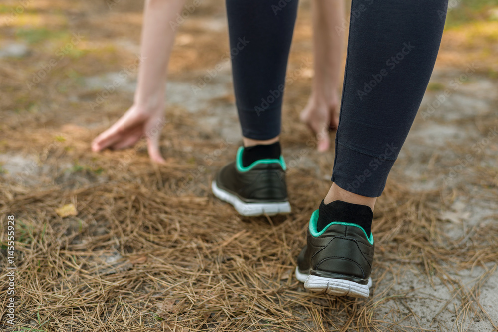 Girl in sports pants and shoes, stands at the start before running, leaning hands, on the nature. Girl in sports pants and shoes, stands at the start before running, leaning hands, on the nature.