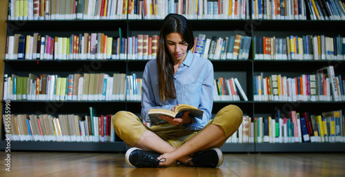 Portrait of a beautiful young woman smiling happy in a library holding books after doing a search and after studying. Concept  educational  portrait  library  and studious.