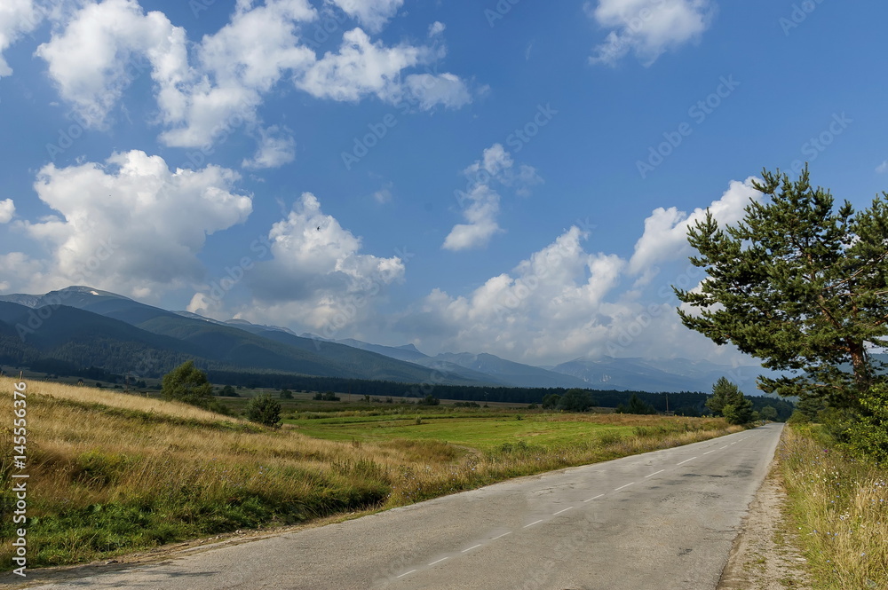 Majestic mountain top overgrown with coniferous forest, valley, glade and road, Rila mountain, Bulgaria