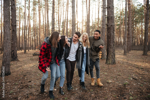 Smiling group of friends walking outdoors in the forest.