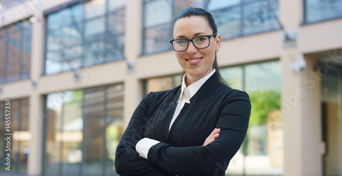 A woman in a suit, looks in camera and smiles proud and sure of himself, in the business centre. Concept of politics, business, finance, banking, insurance and testimonials for political campaign. 