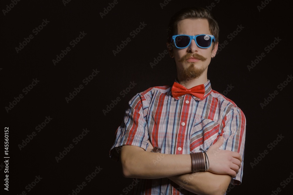 Young caucasian handsome hipster with beard posing in studio on dark background Young caucasian handsome hipster with beard posing in studio on dark background