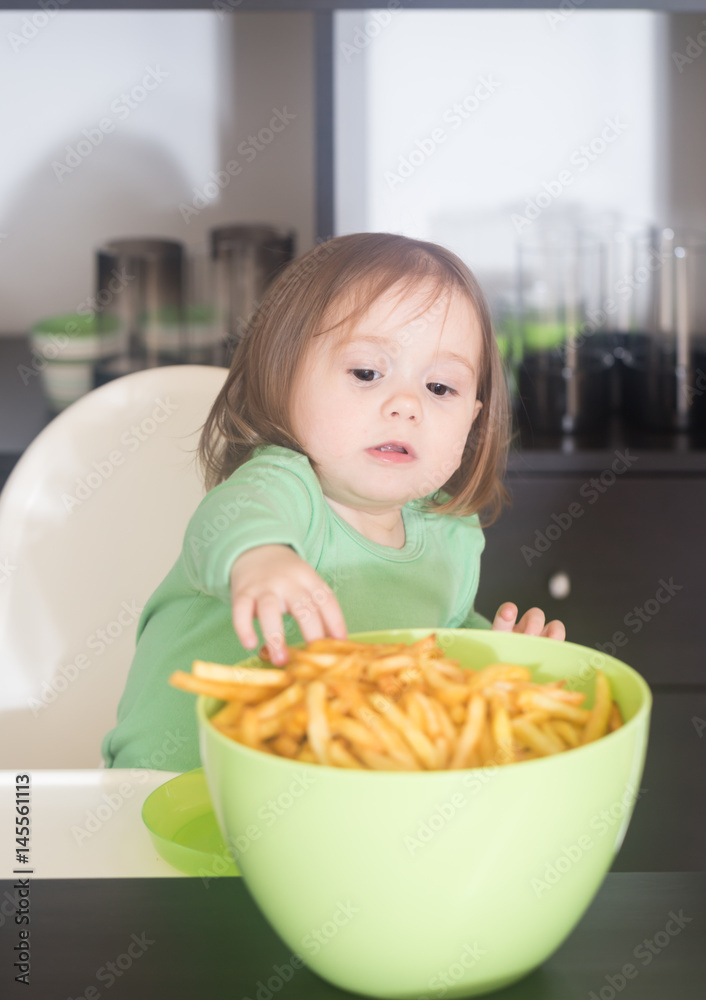 Stealing pomfrit.Cute little girl stealing pomfrit from a bowl Stealing pomfrit.Cute little girl stealing pomfrit from a bowl