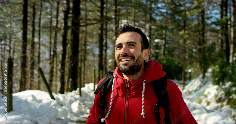 beautiful young man stops to look at the nature around and breathing continuously down to turn on itself in a natural background and wearing a red sweatshirt