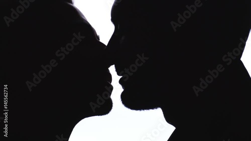 Silhouette of gay couple kissing passionately photo
