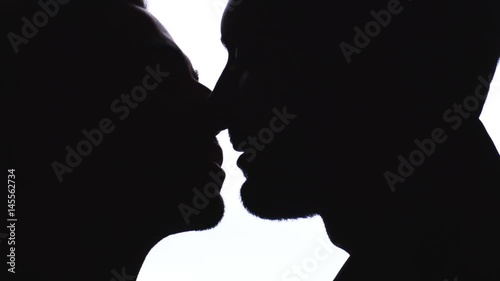 Silhouette of gay couple kissing passionately
