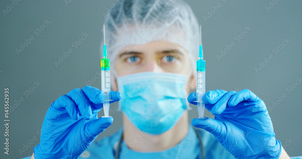 A doctor or scientist in laboratory holding a syringe with liquid vaccines for children or older adults, or cure animal diseases. Concept:diseases,medical care,science, anesthesia,euthanasia,diabetes. A doctor or scientist in laboratory holding a syringe with liquid vaccines for children or older adults, or cure animal diseases. Concept:diseases,medical care,science, anesthesia,euthanasia,diabetes.