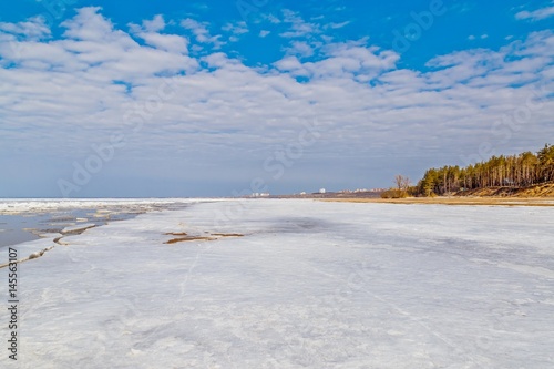 Spring melting of ice on the Volga River against the background of mountains and blue sky