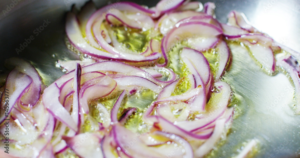 Obraz premium Slow motion of chef cutting the onion in small slices on a wooden table of a professional kitchen, concept of Italian and Mediterranean diet , diet concept and healthy life 