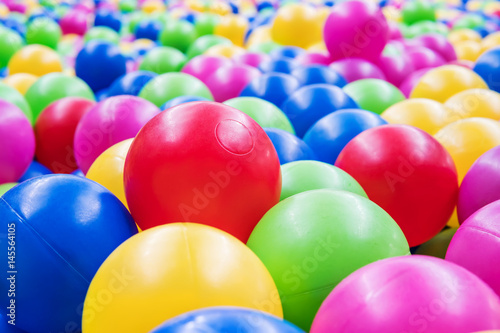 A large red ball among a multitude of plastic colored children balls
