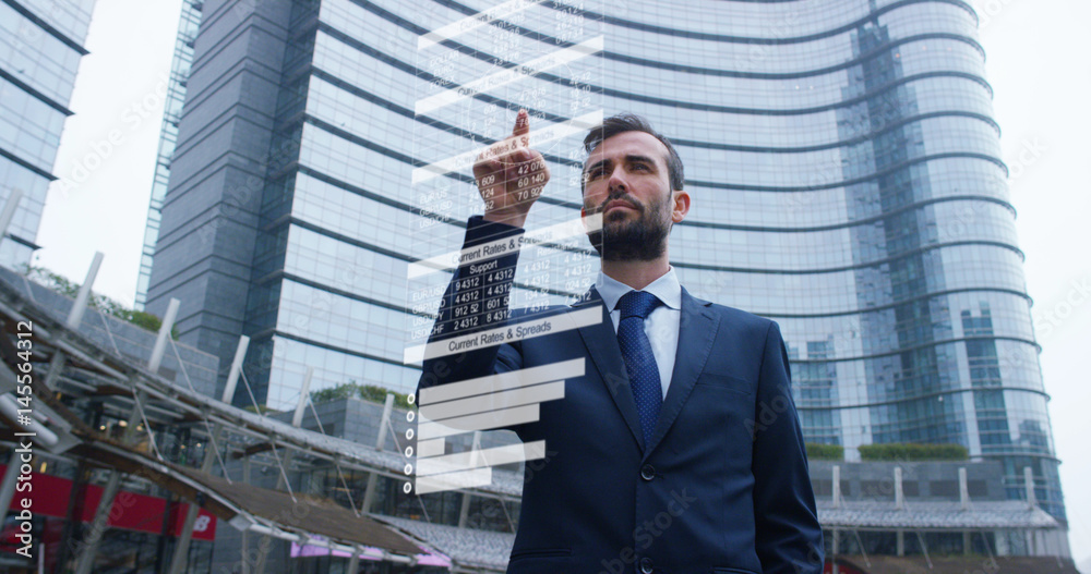 A businessman in a suit uses holography and augmented reality to see in 3D graphics financial economics and skyscraper in the background. Concept: immersive technology, business, economy, futuristic	