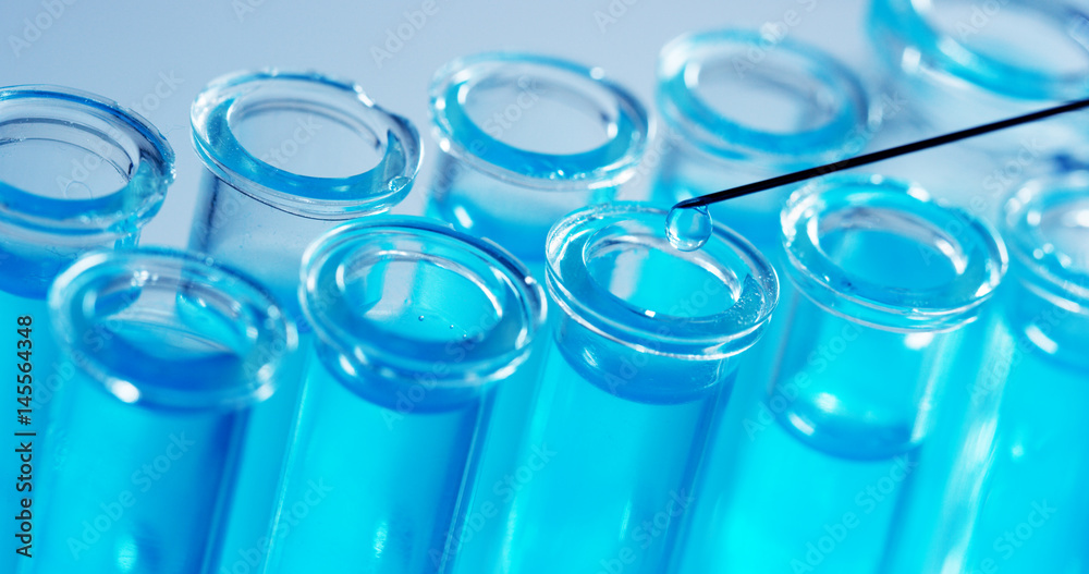 In a laboratory, a scientist with a pipette analyzes a colored liquid to extract the DNA and molecules in the test tubes. Concept: research, biochemistry, nature, pharmaceutical medicine In a laboratory, a scientist with a pipette analyzes a colored liquid to extract the DNA and molecules in the test tubes. Concept: research, biochemistry, nature, pharmaceutical medicine