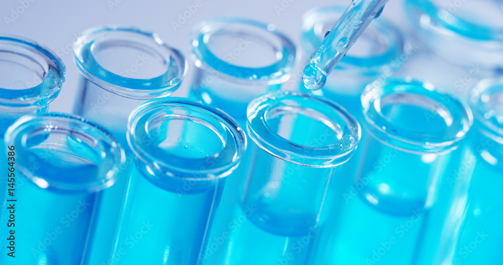 In a laboratory, a scientist with a pipette analyzes a colored liquid to extract the DNA and molecules in the test tubes. Concept: research, biochemistry, nature, pharmaceutical medicine In a laboratory, a scientist with a pipette analyzes a colored liquid to extract the DNA and molecules in the test tubes. Concept: research, biochemistry, nature, pharmaceutical medicine
