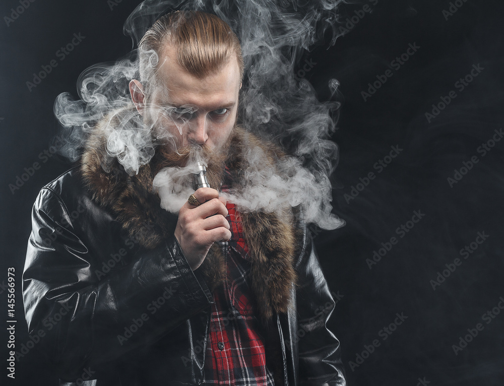Vaping man holding a mod. A cloud of vapor. Black background. Studio shooting.