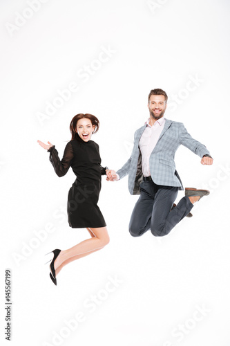 Happy young loving couple jumping isolated