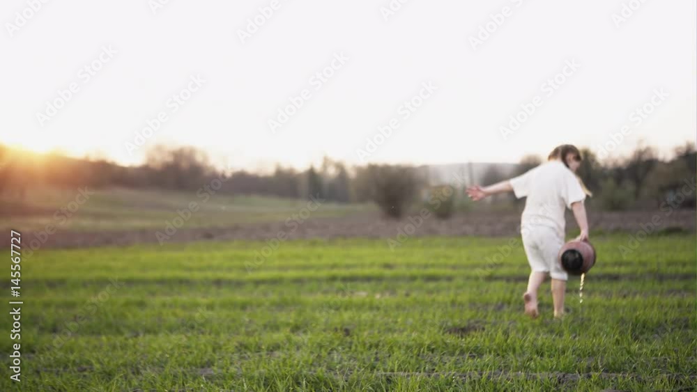 Little girl walks and water the green field Little girl walks and water the green field