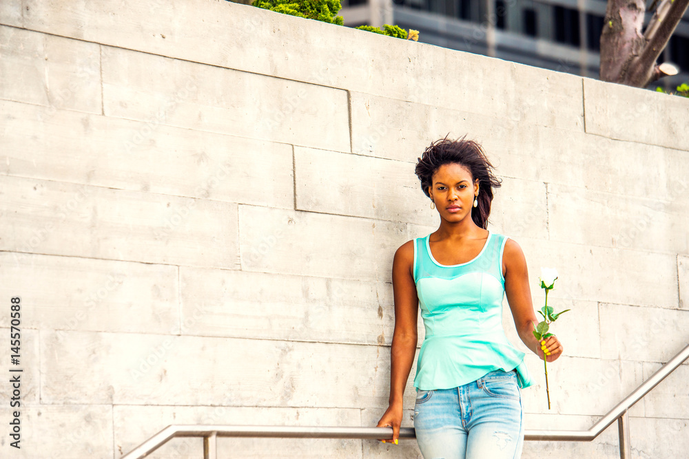 Young African American woman waiting you with white rose in New York in windy day