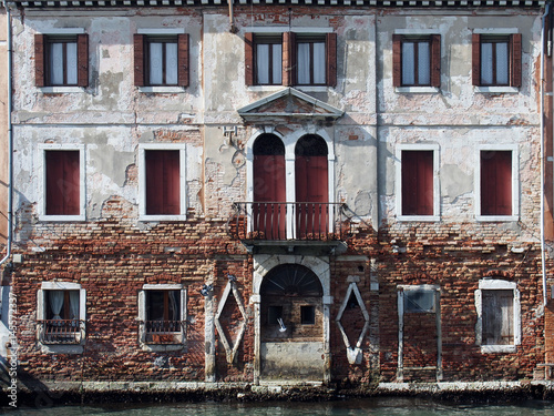 old building alongside canal in venice with shutters and doorway opening onto the canal photo