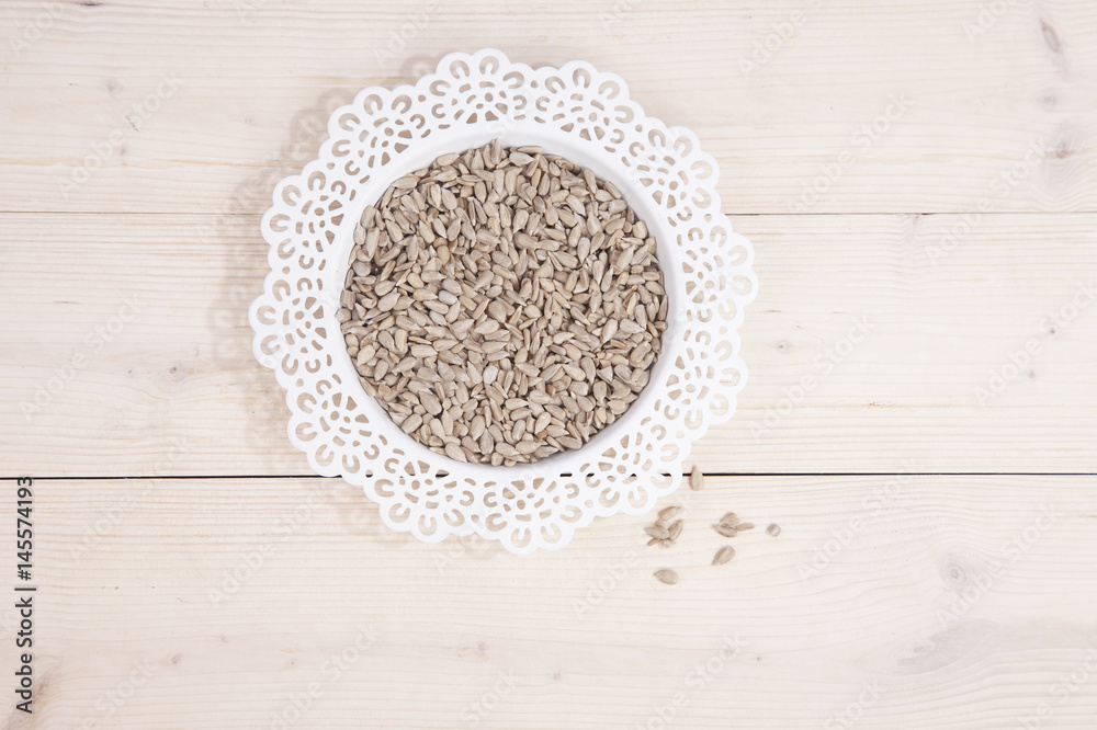 Sunflower seeds in white bowl on wooden background Sunflower seeds in white bowl on wooden background