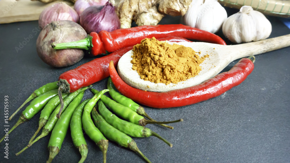 Asian cuisine ingredients - red pepper green pepper and turmeric powder on black background Asian cuisine ingredients - red pepper green pepper and turmeric powder on black background