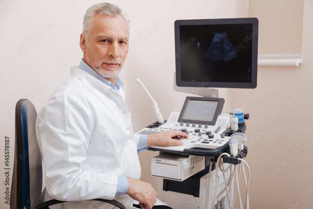 Bearded aged doctor using medical equipment in the hospital Bearded aged doctor using medical equipment in the hospital