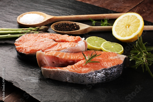 Fresh raw salmon fish steaks with fresh herbs on stone background