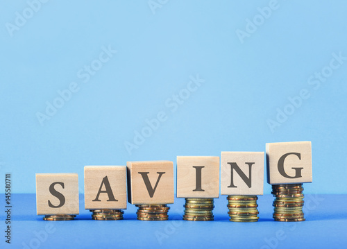 SAVING concept with wooden blocks, coins on table.