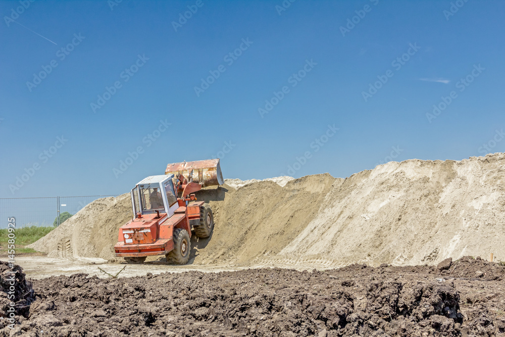Bulldozer is making pile of soil by pulling ground up on heap at construction site, project in progress Bulldozer is making pile of soil by pulling ground up on heap at construction site, project in progress