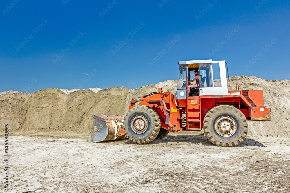 Bulldozer is making pile of soil by pulling ground up on heap at construction site, project in progress Bulldozer is making pile of soil by pulling ground up on heap at construction site, project in progress