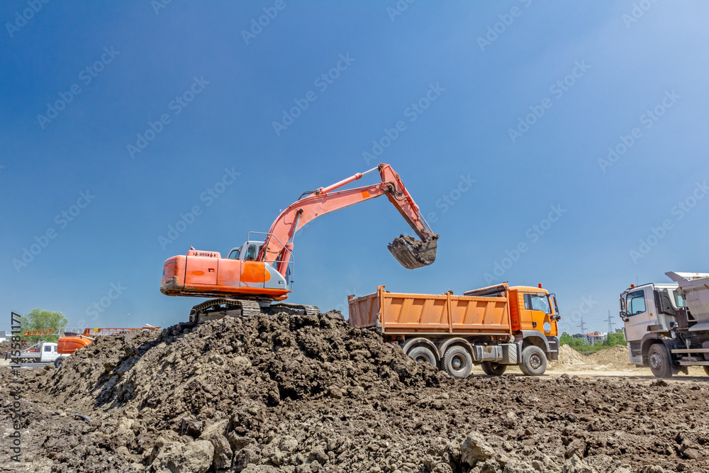 Excavator is loading a truck on building site Excavator is loading a truck on building site