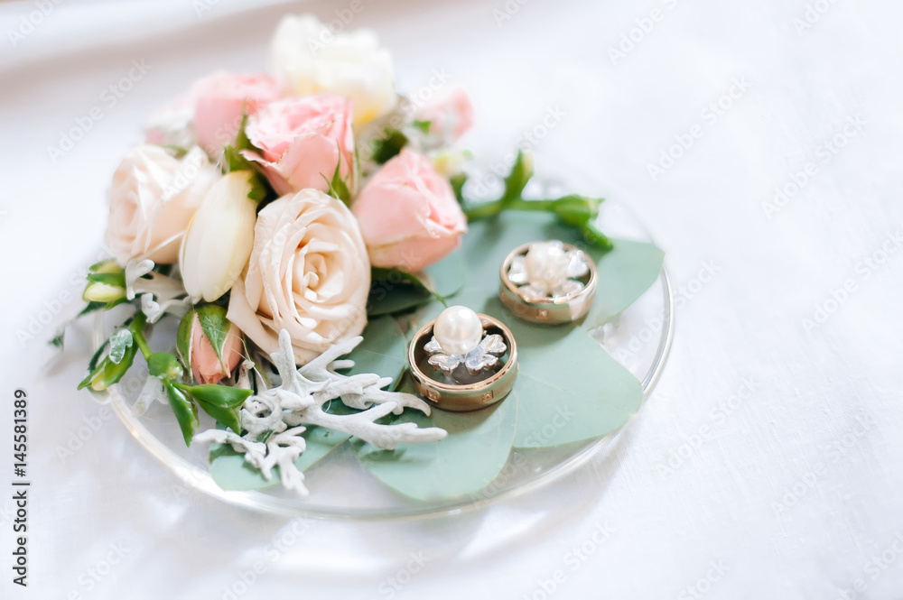 On a plate are wedding rings, earrings and flowers roses. On a plate are wedding rings, earrings and flowers roses.