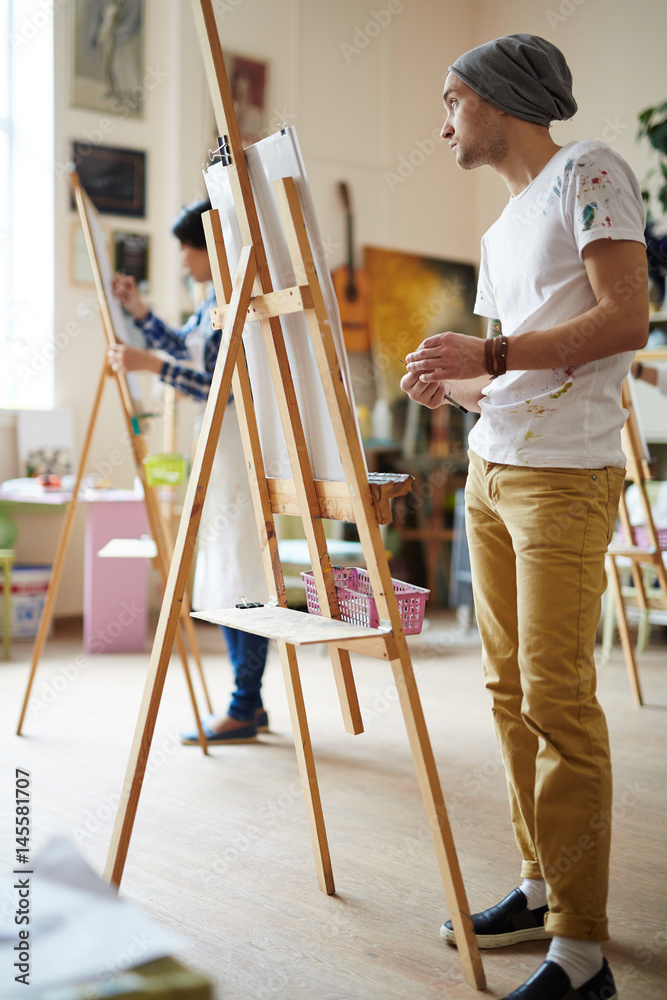 Obraz premium Learner of art-school standing by easel