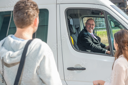 Smiling Driver In Van Looking At Passengers At Airport