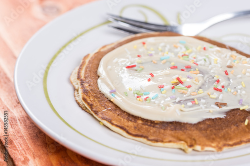 American pancakes topped with chocolate cream and colorful sprinkles