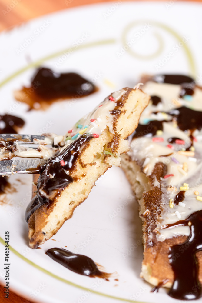 Slice of american pancake topped with chocolate cream and sprinkles on the fork closeup macro Slice of american pancake topped with chocolate cream and sprinkles on the fork closeup macro