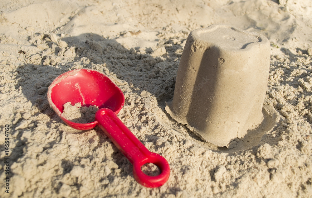 Sand toys, a red bucket and a scoop on the sand,