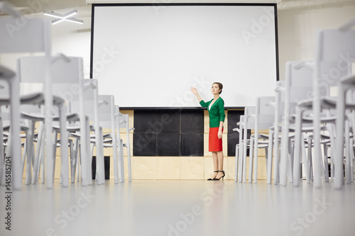 Young teacher pointing at whiteboard while explaining new topic