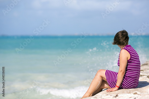 Woman looking at the sea. Focus point on the caucasian lady.