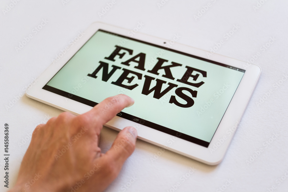 Fake News - user of digital device reads false information hoax, disinformation, propaganda. Misleading and brainwashing of reader Fake News - user of digital device reads false information hoax, disinformation, propaganda. Misleading and brainwashing of reader