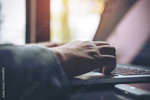 Closeup image of a business woman's hands working and typing on laptop keyboard on glass table