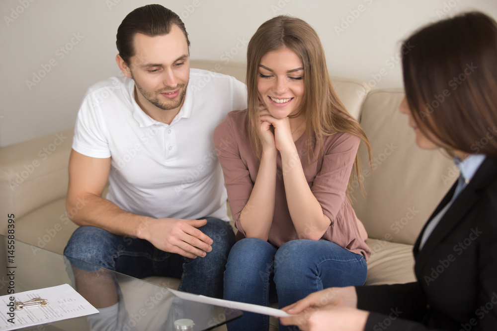 Happy couple talking over terms and conditions of home purchase agreement to real estate broker, future property owners discussing mortgage interest with advisor, making deal to rent apartment Happy couple talking over terms and conditions of home purchase agreement to real estate broker, future property owners discussing mortgage interest with advisor, making deal to rent apartment
