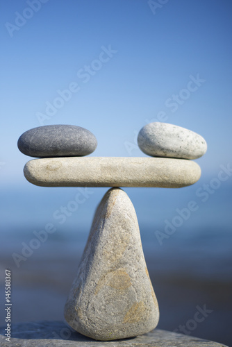 Balancing of black and white pebbles on the top of stone. Symbol of scales is made of stones.