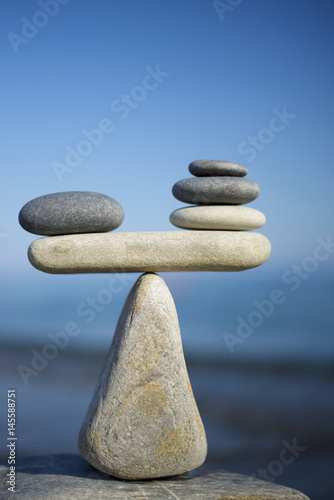 Balancing of black and white pebbles on the top of stone. Symbol of scales is made of stones.